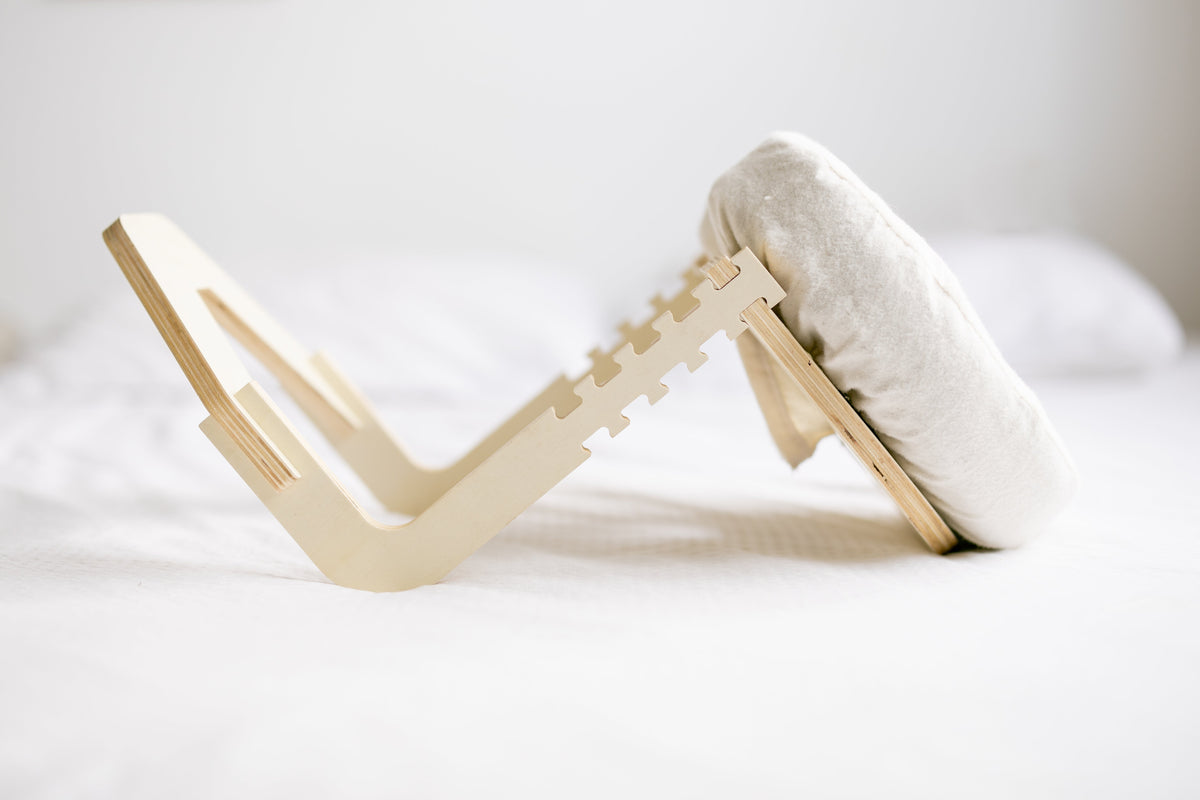 Das aufgeklappte Holzgestell auf einem weißen Bett