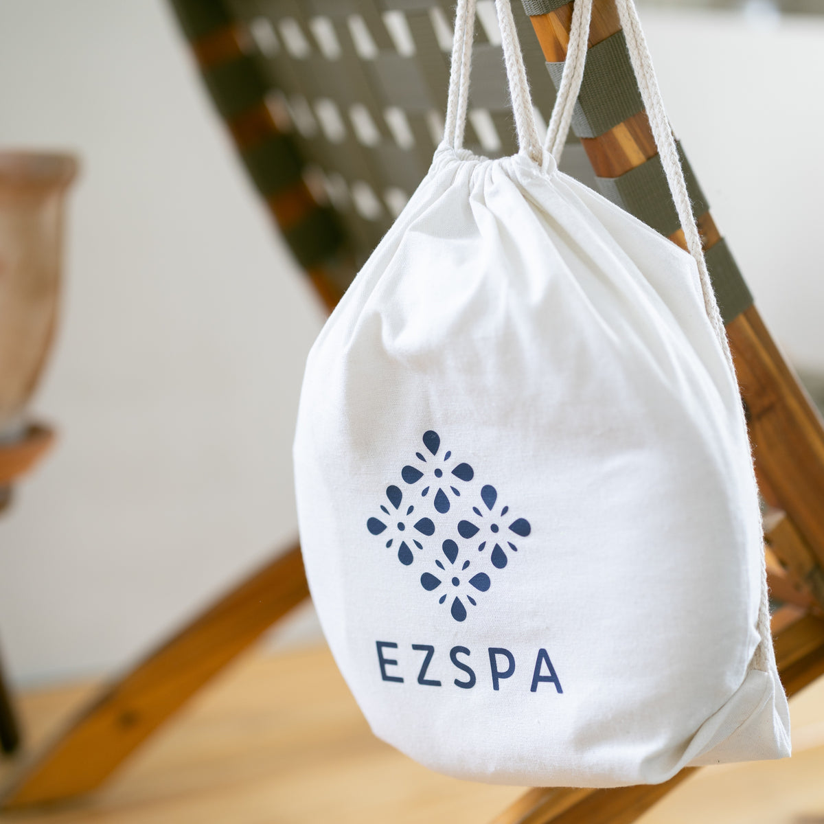 Die Baumwoll-Tragetasche von Ezspa mit dem Logo, hängend an einem Stuhl
