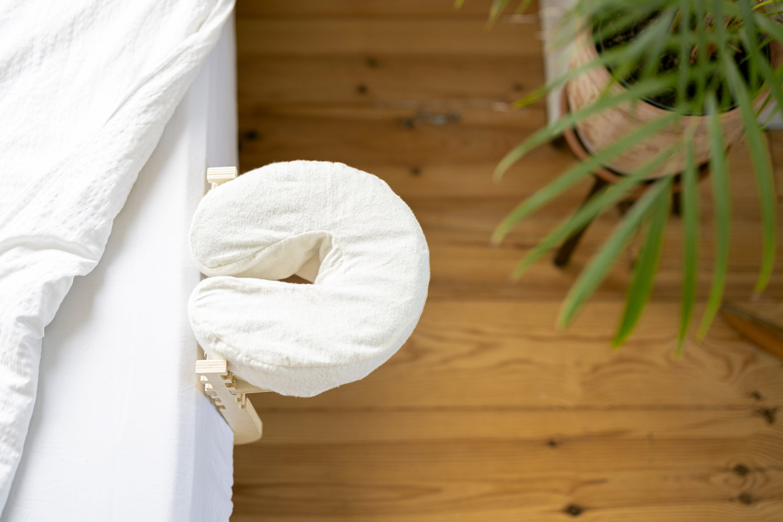 Die Ezspa Bettmassage Set am Rand eines gemachten Betts, darunter ein Holzboden